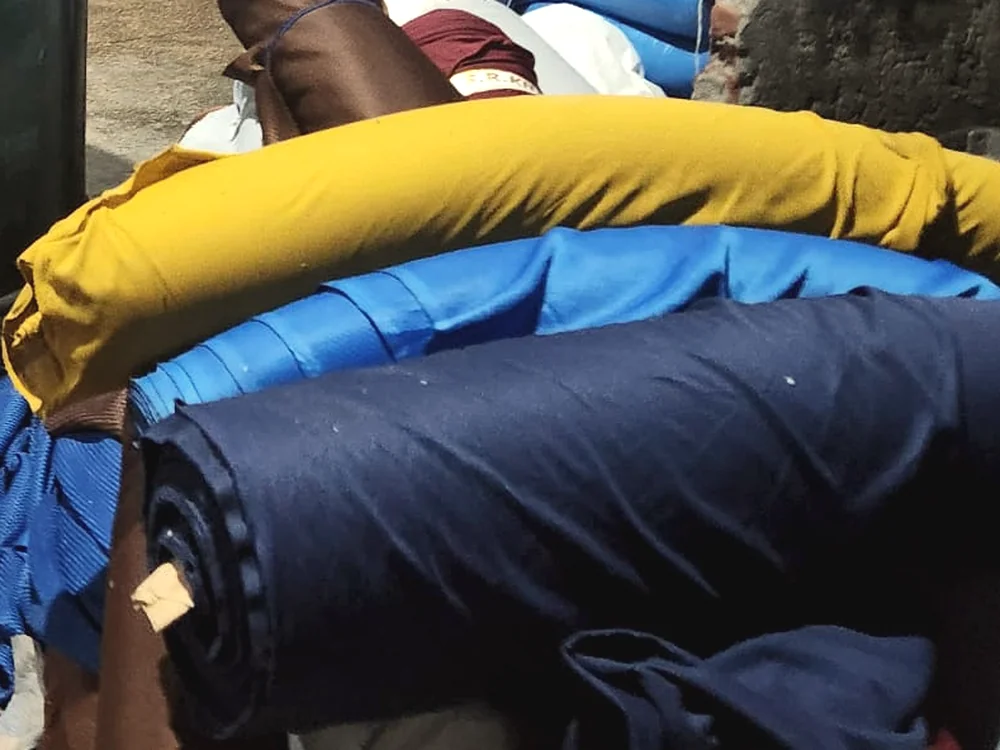 Close-up of rolled knit fabrics in navy, yellow and blue staged for production